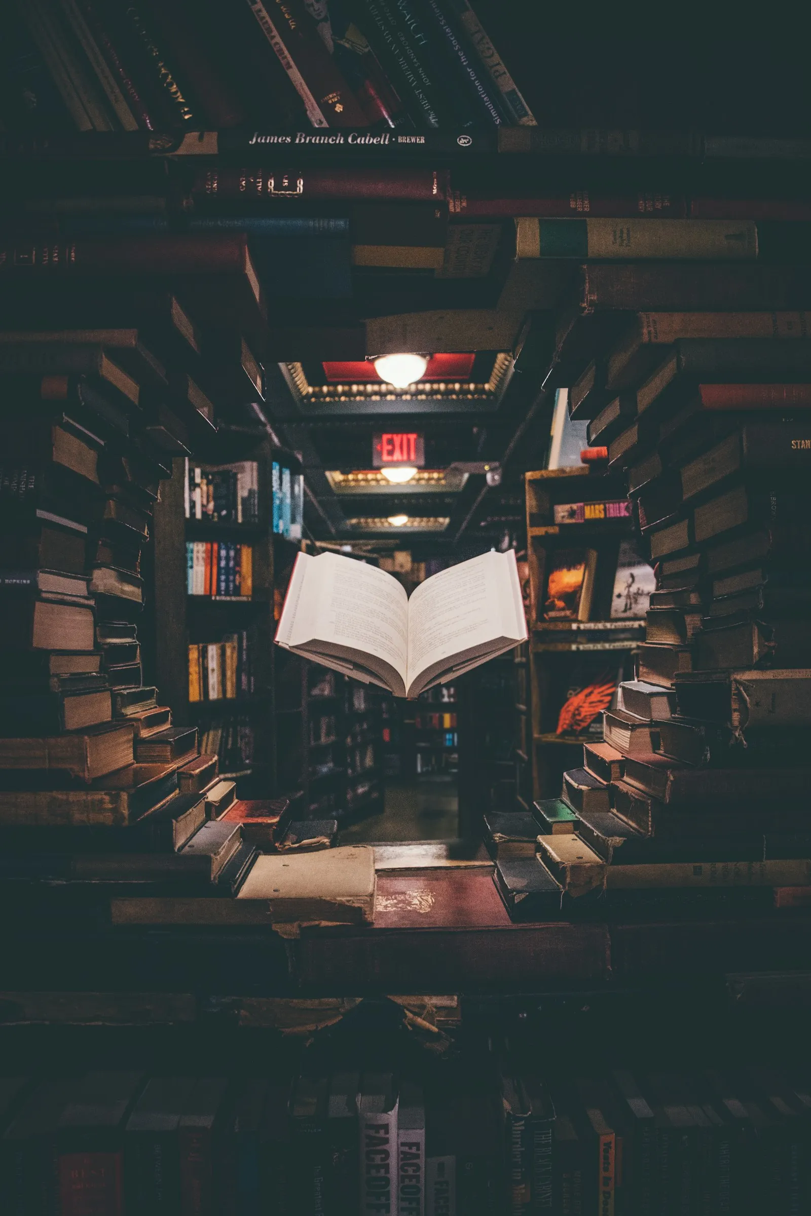 View of a floating open book above stacked books in a library